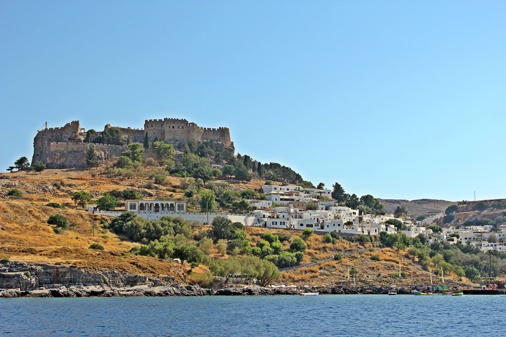 Blick vom Meer aus auf die weißen Häuser von Lindos die unterhalb der Akropolis liegen. Ausflugstipp für Rhodos