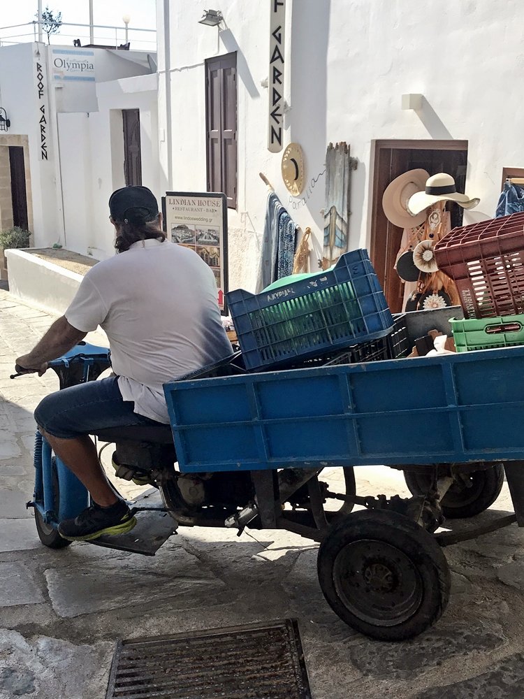 Zu einem Transportfahrzeug umgebauter Roller der durch die engen Gassen Lindos fährt. Ausflugstipp für Rhodos