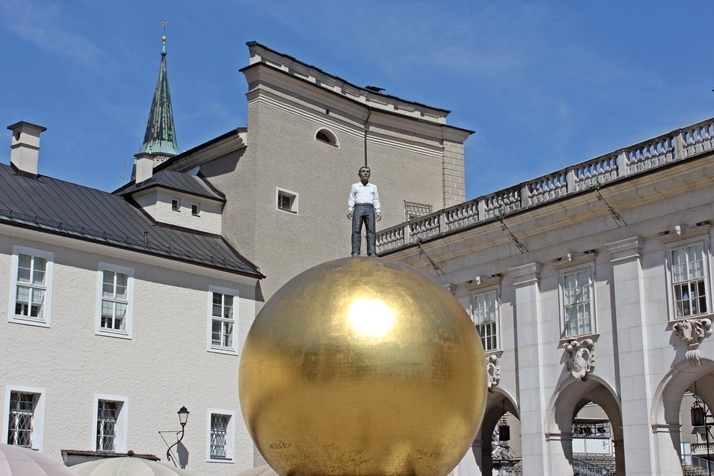 Gesamtkunstwerk Sphaera. Hier der Mann auf der goldenen Kugel. Das Kunstwerk befindet sich auf dem Kapitelplatz Salzburgs.