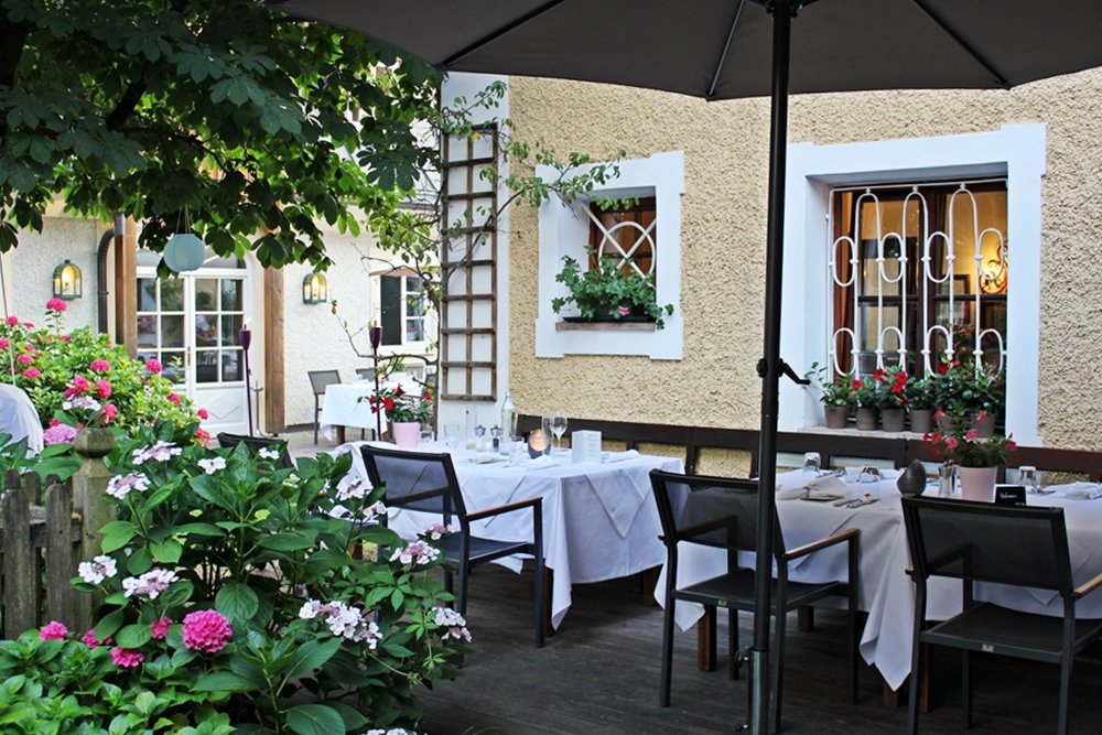 Weißgedeckte Tische unter Kastanienbaum, Hauben-Restaurant im Romantik Hotel GMACHL