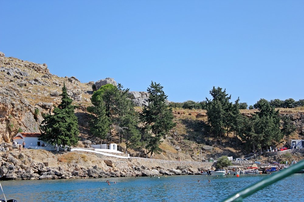 Blick vom Boot auf die weiße Kapelle in der St. Pauls Bay in Lindos, Ausflugstipp für Rhodos